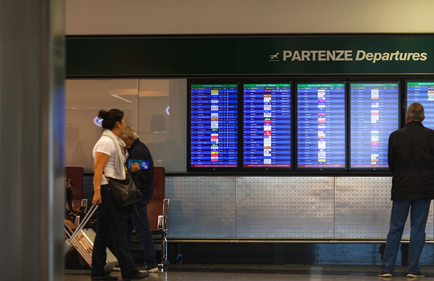 Area partenze dell'aeroporto di Milano Malpensa con degli schermi sullo sfondo